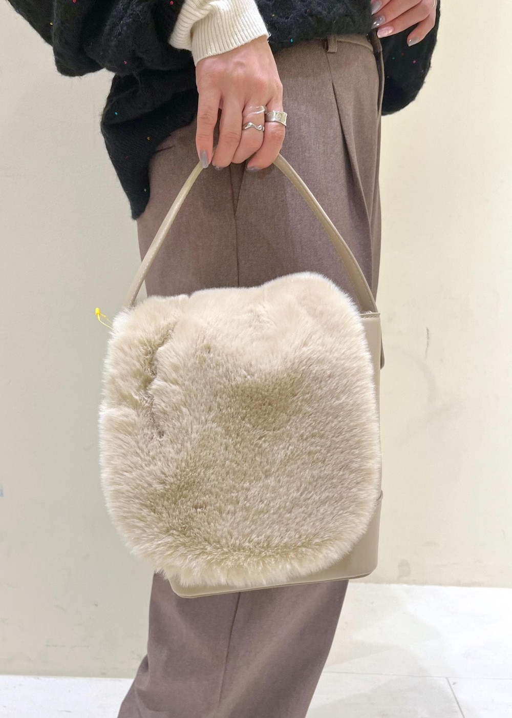 ベージュ系のスラックス、ホワイト系のニット/セーター、ベージュ系のショルダーバッグを着用したレディースの冬コーディネートの9枚目の写真