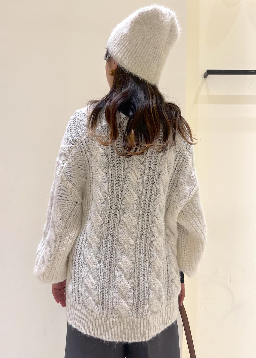 ブラック系のニット/セーター、ブラック系のブーツ、ブラウン系のショルダーバッグを着用したレディースの秋コーディネートの7枚目の写真