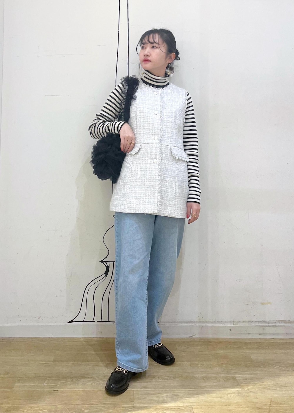 ホワイト系のニット/セーター、ブルー系のデニムパンツ、ブラック系のレインシューズを着用したレディースの冬コーディネートの2枚目の写真