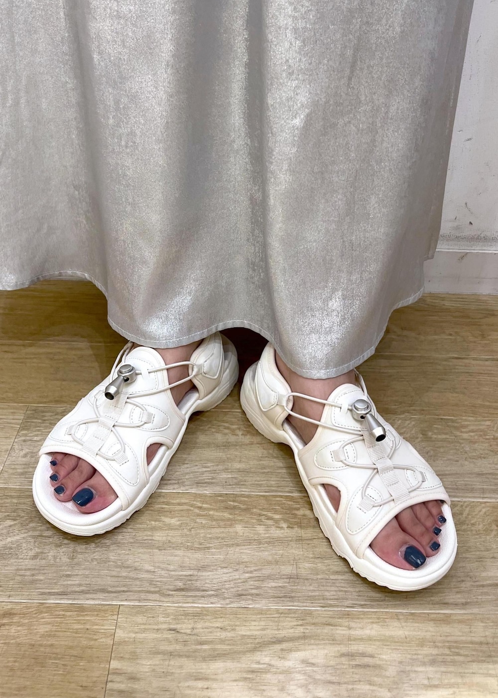 シルバー系のスカート、ブラック系のTシャツ/カットソー、ホワイト系のサンダルを着用したレディースの夏コーディネートの10枚目の写真