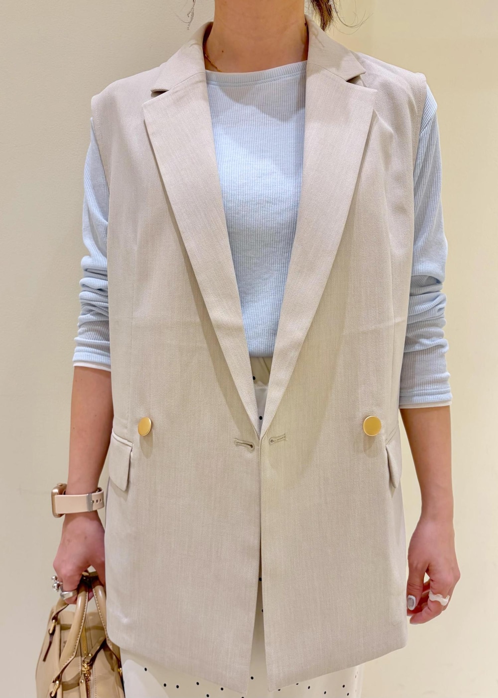 ベージュ系のボストンバッグ、ブルー系のTシャツ/カットソー、ベージュ系のベストを着用したレディースの春コーディネートの5枚目の写真