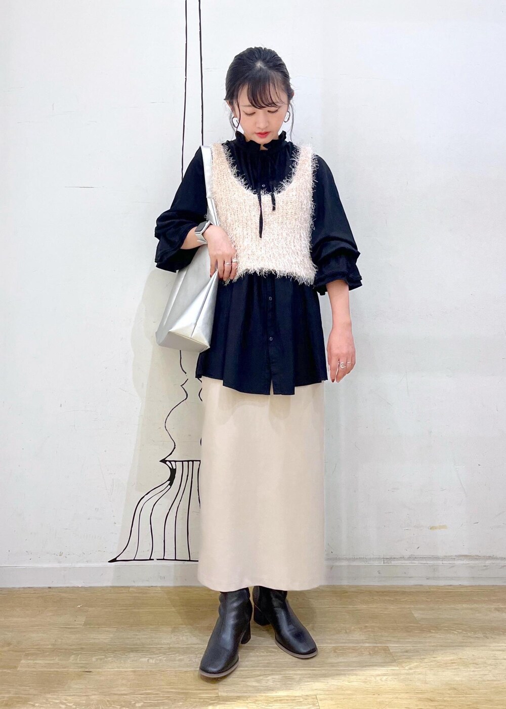 ベージュ系のスカート、ベージュ系のベスト、ブラック系のシャツ/ブラウスを着用したレディースの秋コーディネートの3枚目の写真