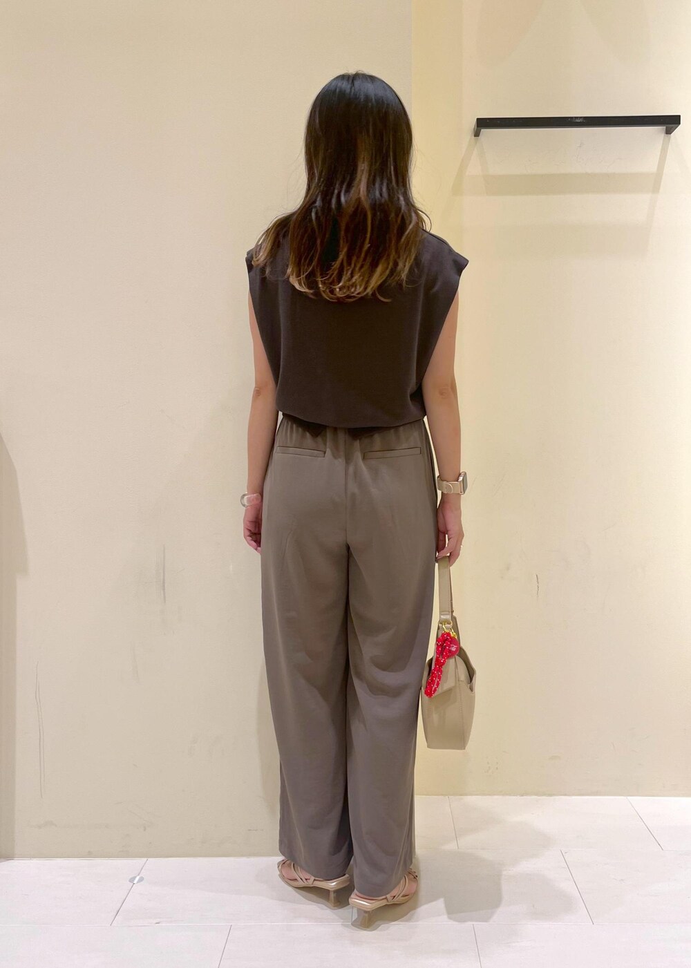 ゴールド系のサンダル、ベージュ系のハンドバッグ、グレー系のTシャツ/カットソーを着用したレディースの夏コーディネートの3枚目の写真