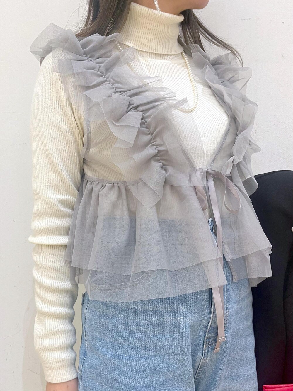 ブルー系のデニムパンツ、レッド系のトートバッグ、ブラック系のその他アウターを着用したレディースの冬コーディネートの5枚目の写真