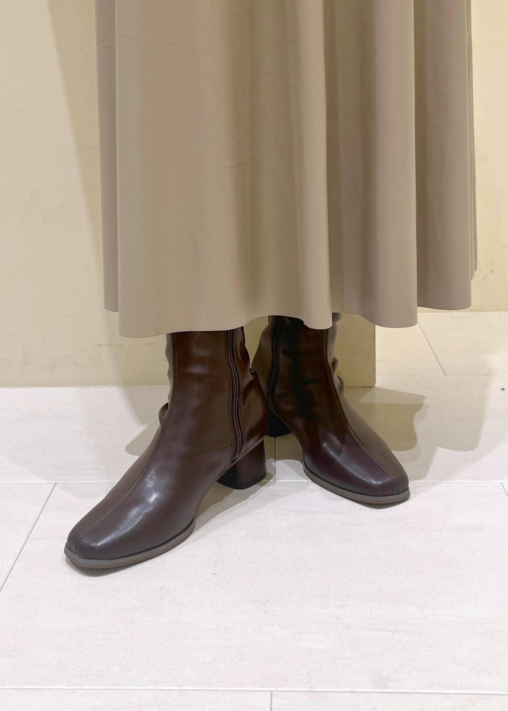 レッド系のショルダーバッグ、ベージュ系のスカート、ホワイト系のカーディガン/ボレロを着用したレディースの秋コーディネートの10枚目の写真