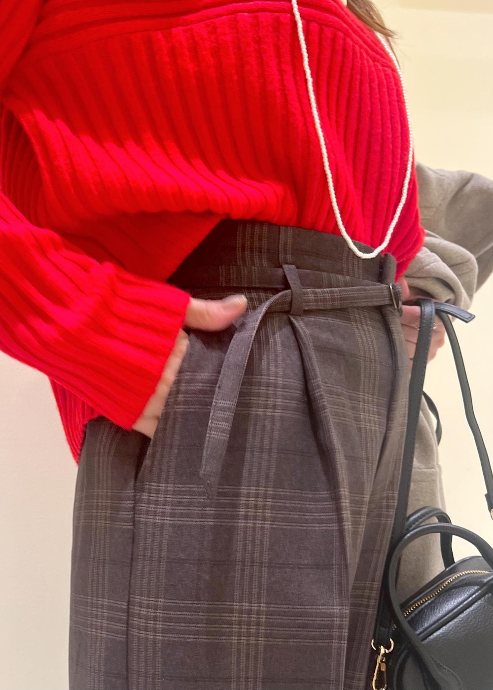 ブラック系のショルダーバッグ、レッド系のニット/セーター、ブラウン系のピーコートを着用したレディースの冬コーディネートの6枚目の写真