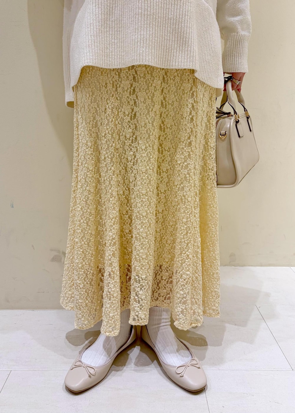 ホワイト系のバレエシューズ、ホワイト系のニット/セーター、ホワイト系のボストンバッグを着用したレディースの冬コーディネートの7枚目の写真