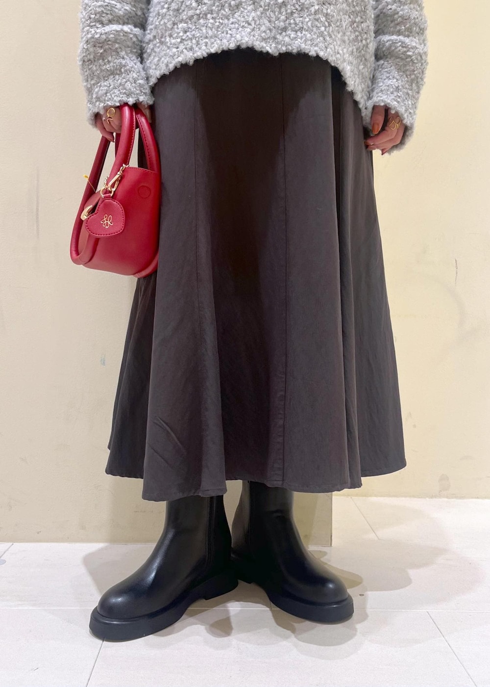 ホワイト系のニット/セーター、グレー系のスカート、レッド系のショルダーバッグを着用したレディースの冬コーディネートの7枚目の写真