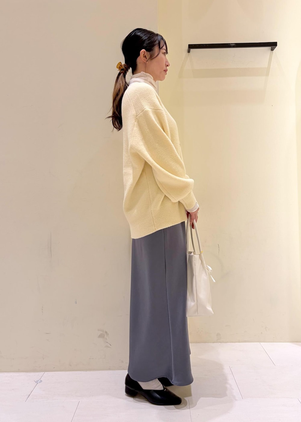 ベージュ系のカーディガン/ボレロ、ホワイト系のトートバッグ、ホワイト系のTシャツ/カットソーを着用したレディースの冬コーディネートの2枚目の写真