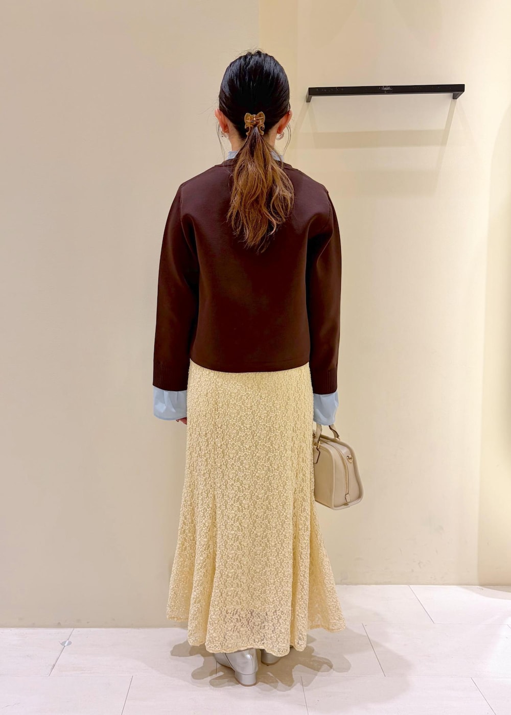 ホワイト系のボストンバッグ、ベージュ系のスカート、ブラウン系のカーディガン/ボレロを着用したレディースの春コーディネートの3枚目の写真