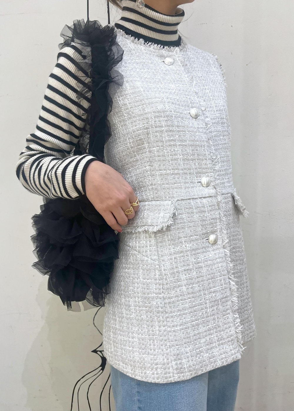 ホワイト系のニット/セーター、ブルー系のデニムパンツ、ブラック系のレインシューズを着用したレディースの冬コーディネートの6枚目の写真