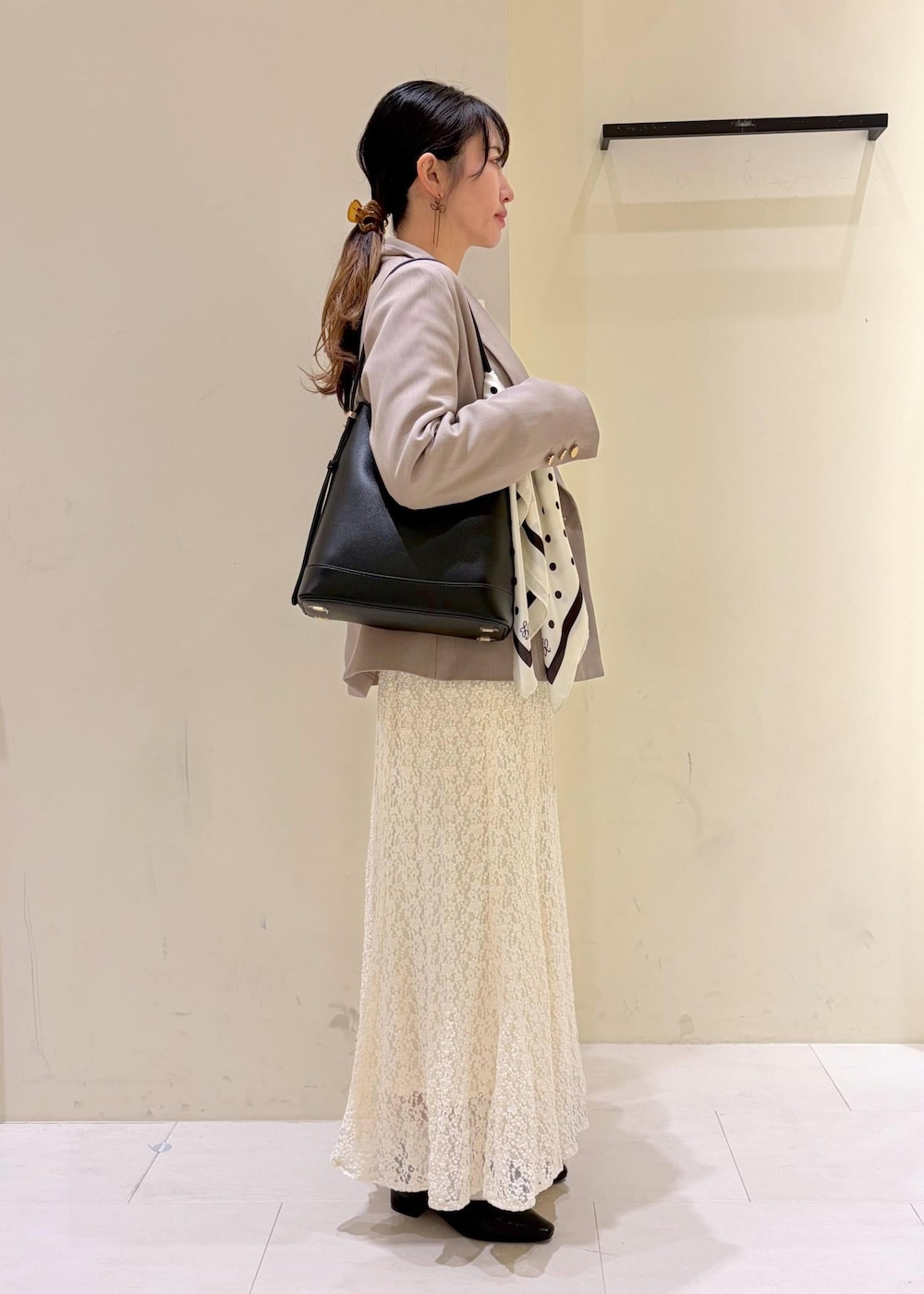 ブラック系のショルダーバッグ、ホワイト系のスカート、ホワイト系のカーディガン/ボレロを着用したレディースの冬コーディネートの2枚目の写真
