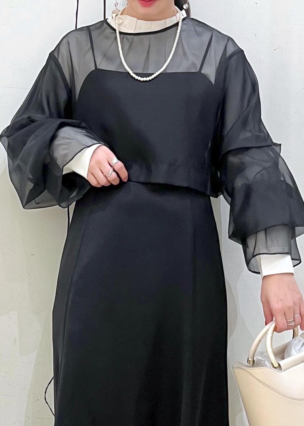 ベージュ系のローファー、ホワイト系のショルダーバッグ、ブラック系のドレスを着用したレディースの冬コーディネートの7枚目の写真