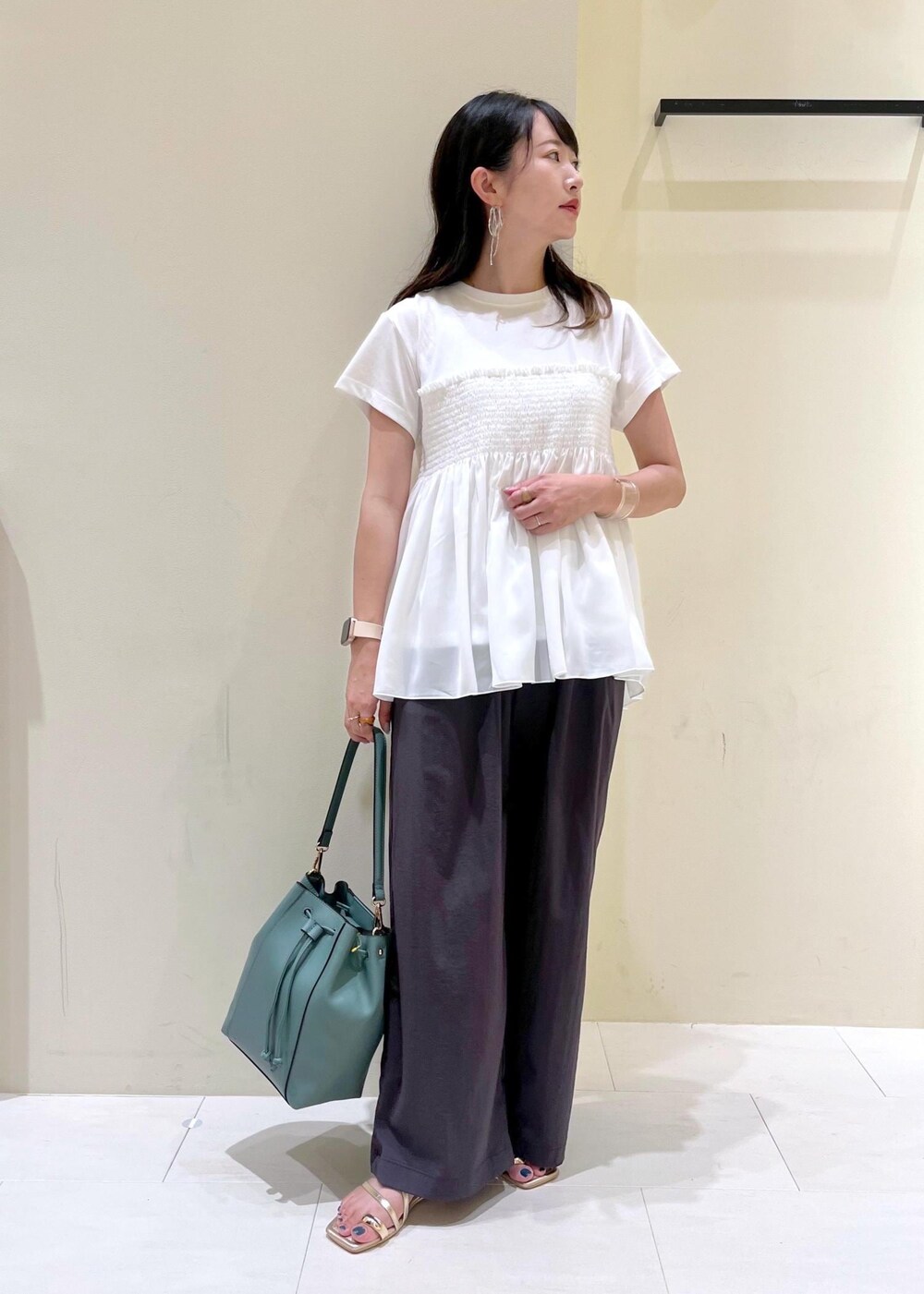 ブルー系のショルダーバッグ、グレー系のその他パンツ、ゴールド系のサンダルを着用したレディースの夏コーディネートの2枚目の写真