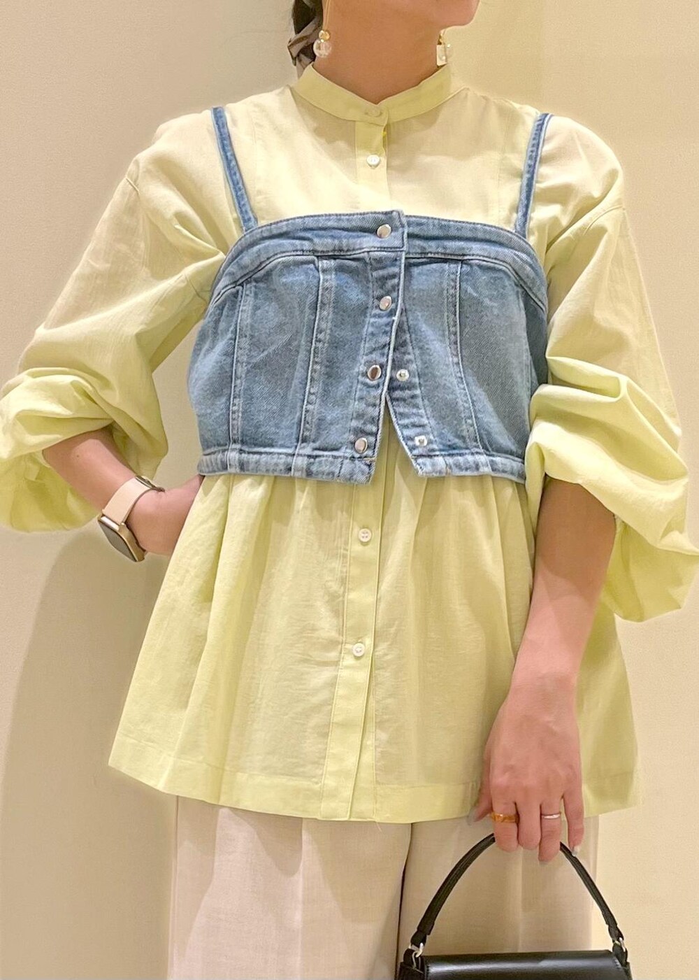 ブラック系のハンドバッグ、ブルー系のベスト、イエロー系のシャツ/ブラウスを着用したレディースの春コーディネートの6枚目の写真