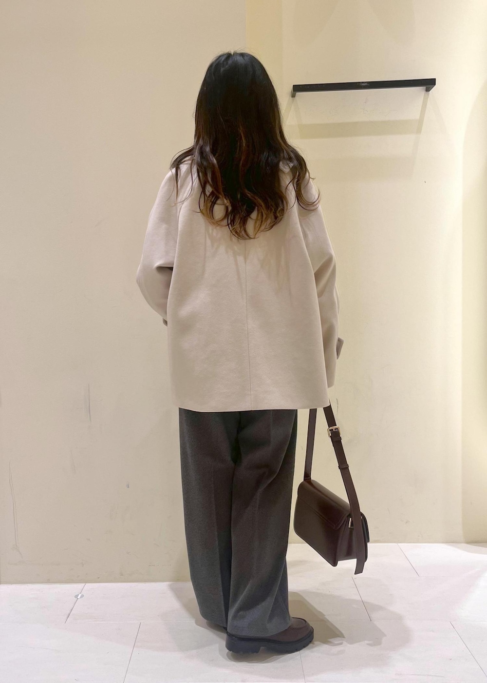 レッド系のショルダーバッグ、ホワイト系のニット/セーター、ベージュ系のその他アウターを着用したレディースの冬コーディネートの3枚目の写真