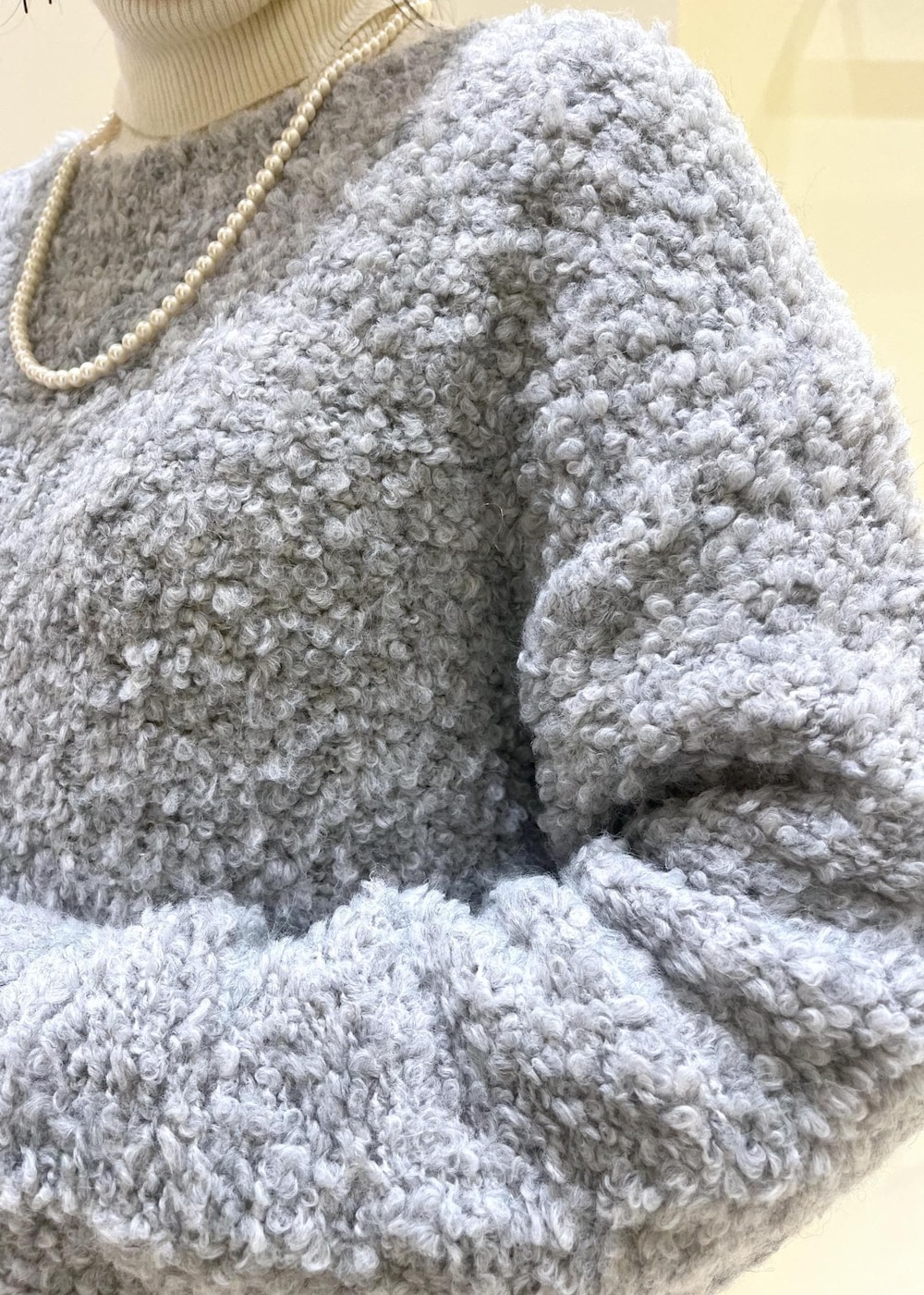 ホワイト系のニット/セーター、グレー系のスカート、レッド系のショルダーバッグを着用したレディースの冬コーディネートの5枚目の写真