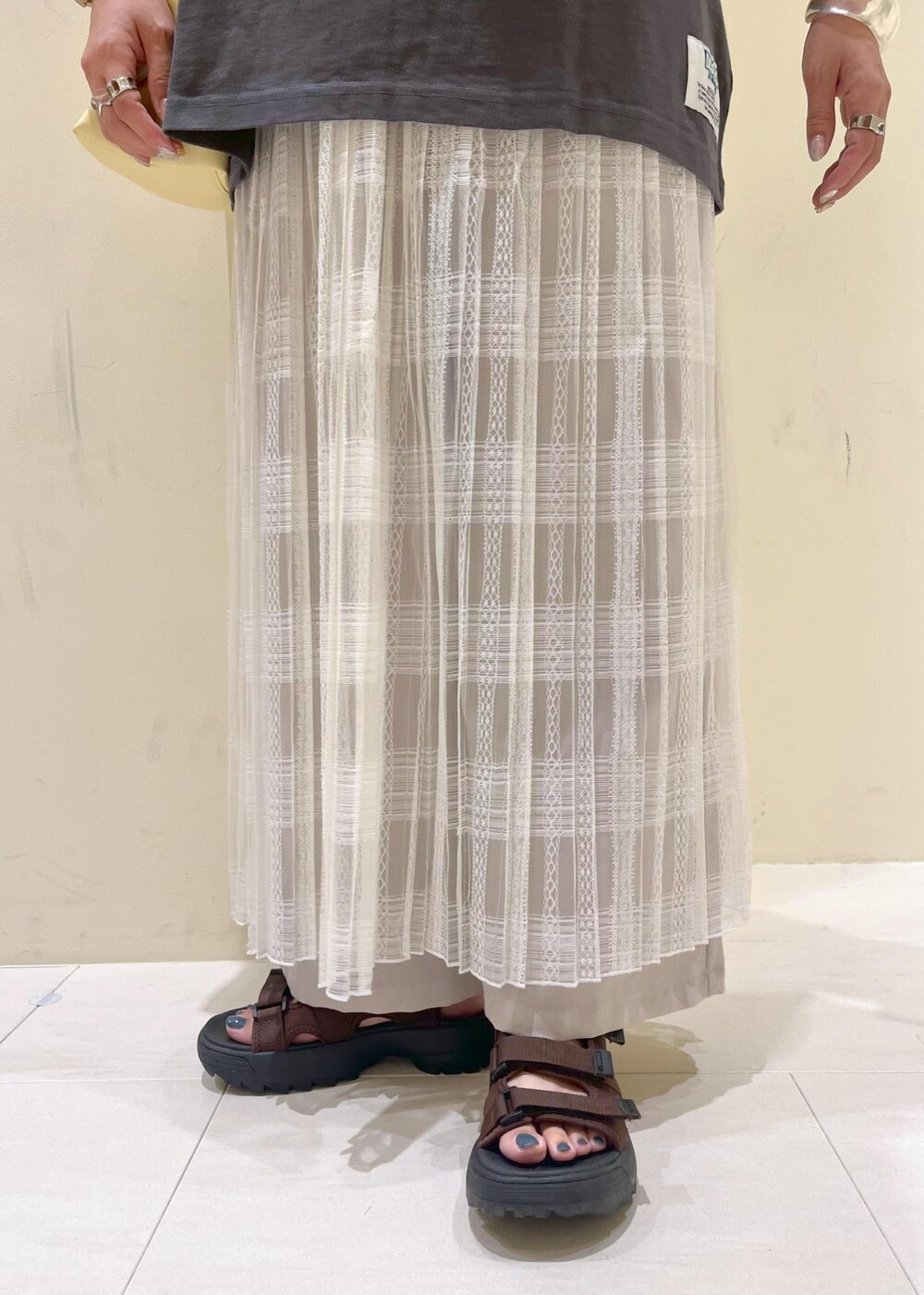 イエロー系のトートバッグ、ホワイト系のスカート、ベージュ系のその他パンツを着用したレディースの夏コーディネートの9枚目の写真