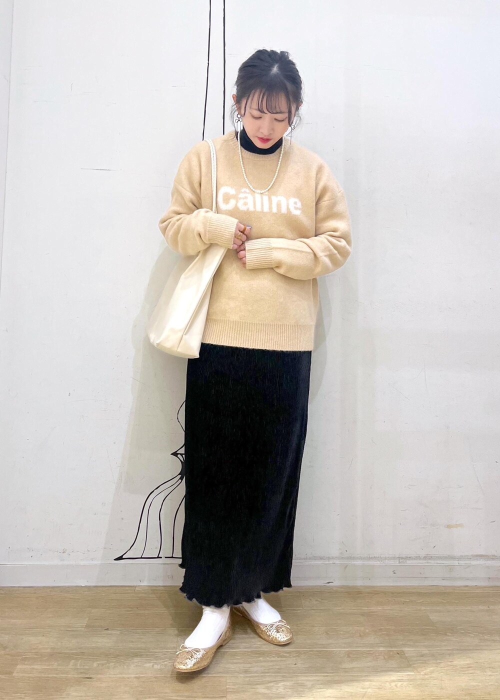 ホワイト系のトートバッグ、ブラック系のニット/セーター、ゴールド系のバレエシューズを着用したレディースの冬コーディネートの2枚目の写真