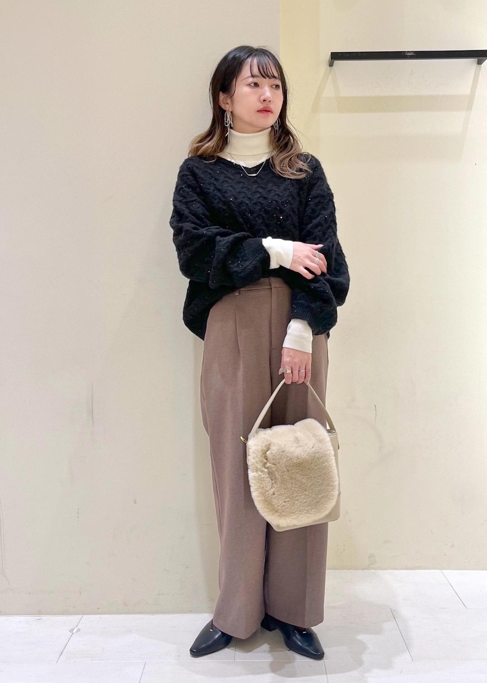 ベージュ系のスラックス、ホワイト系のニット/セーター、ベージュ系のショルダーバッグを着用したレディースの冬コーディネートの2枚目の写真