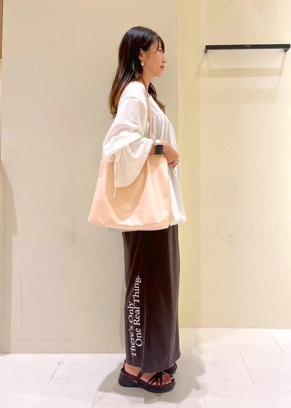 ピンク系のトートバッグ、ブラウン系のサンダル、ホワイト系のシャツ/ブラウスを着用したレディースの夏コーディネートの2枚目の写真