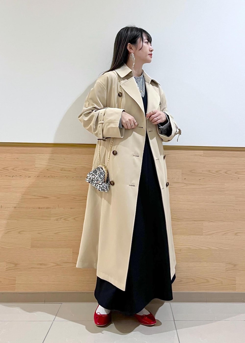 グレー系のショルダーバッグ、ブルー系のシャツ/ブラウス、ベージュ系のトレンチコートを着用したレディースの冬コーディネートの2枚目の写真