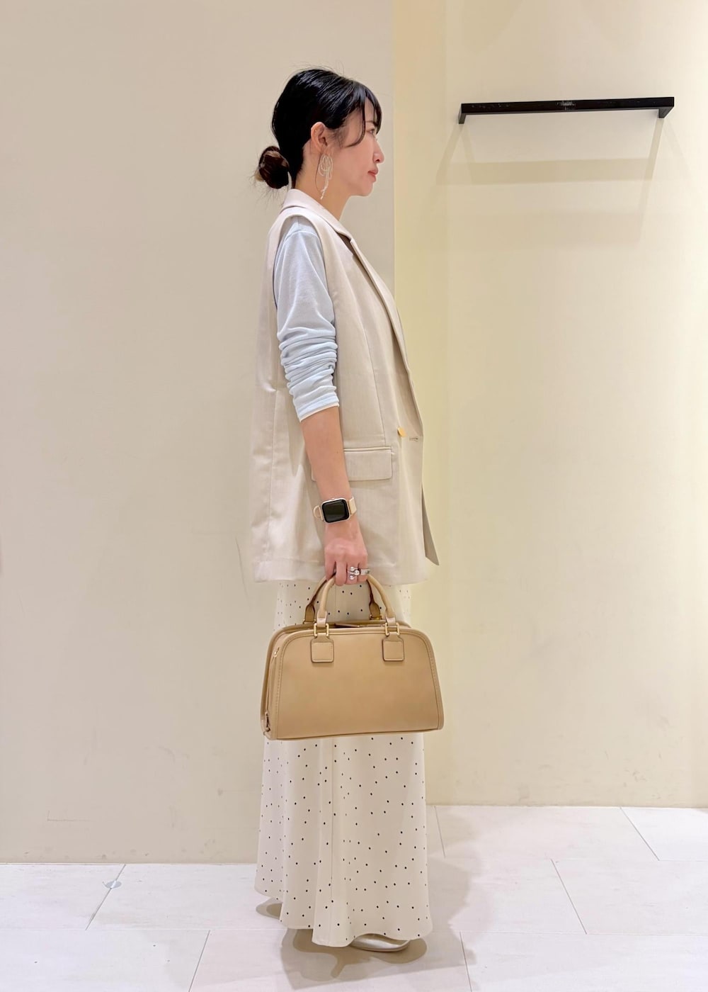 ベージュ系のボストンバッグ、ブルー系のTシャツ/カットソー、ベージュ系のベストを着用したレディースの春コーディネートの2枚目の写真