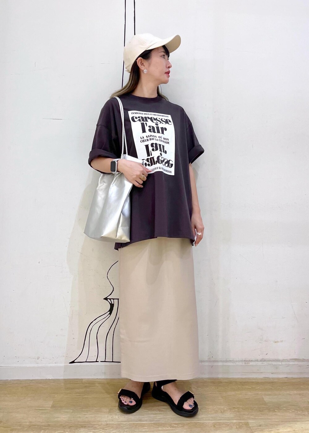 シルバー系のトートバッグ、ブラック系のサンダル、グレー系のTシャツ/カットソーを着用したレディースの夏コーディネートの2枚目の写真