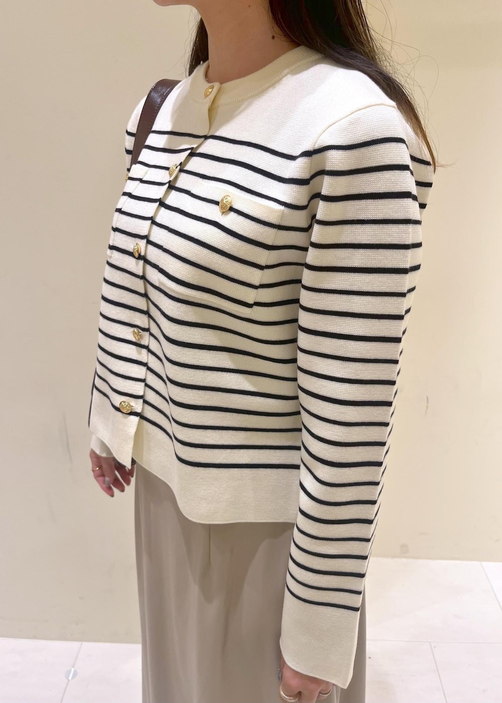 レッド系のショルダーバッグ、ベージュ系のスカート、ホワイト系のカーディガン/ボレロを着用したレディースの秋コーディネートの6枚目の写真