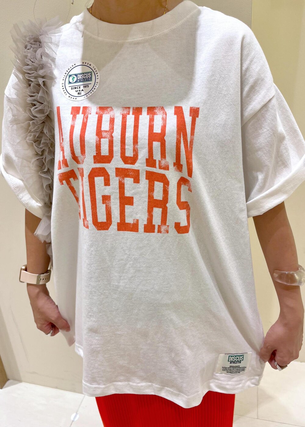 オレンジ系のスカート、ベージュ系のショルダーバッグ、ホワイト系のTシャツ/カットソーを着用したレディースの夏コーディネートの7枚目の写真