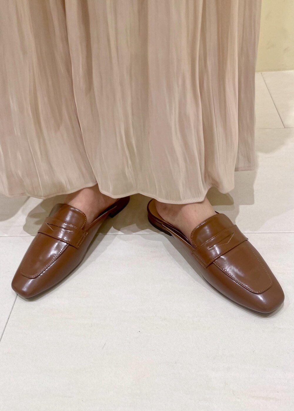 イエロー系のローファー、ベージュ系のスカート、ベージュ系のショルダーバッグを着用したレディースの夏コーディネートの10枚目の写真