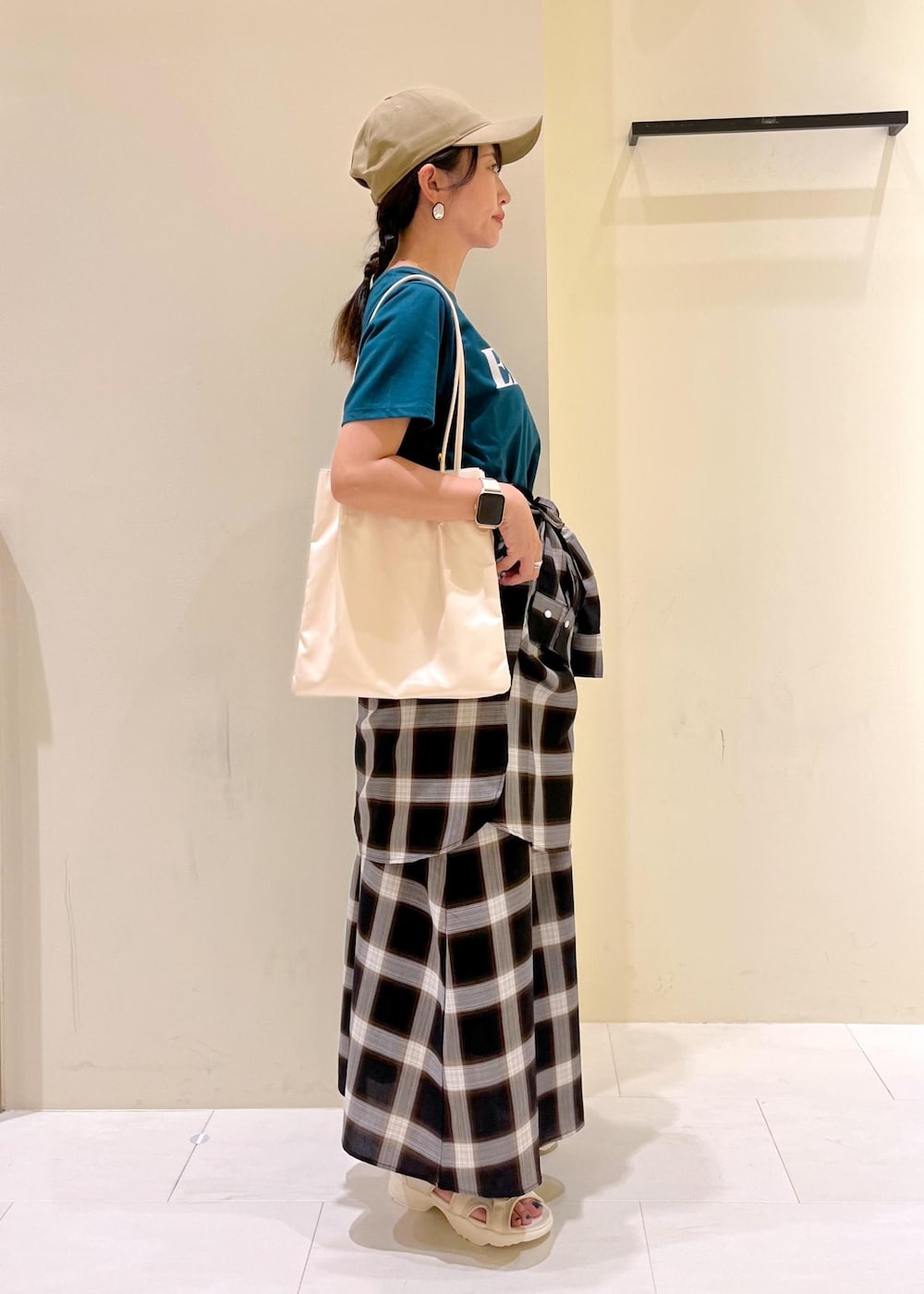 ホワイト系のトートバッグ、ホワイト系のサンダル、ブラック系のワンピースを着用したレディースの夏コーディネートの2枚目の写真