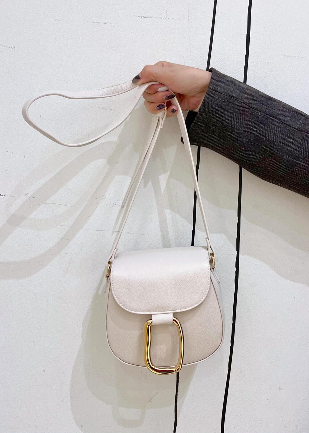 ホワイト系のショルダーバッグ、ブラック系のブーツ、ホワイト系のニット/セーターを着用したレディースの冬コーディネートの9枚目の写真