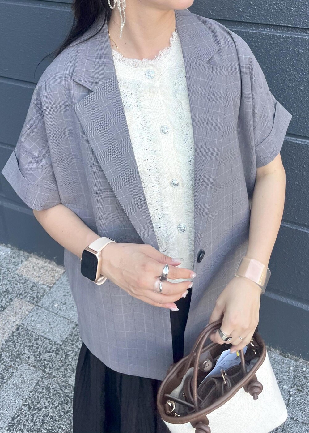 グレー系のテーラードジャケット、ブラウン系のトートバッグ、ブラック系のスカートを着用したレディースの夏コーディネートの10枚目の写真
