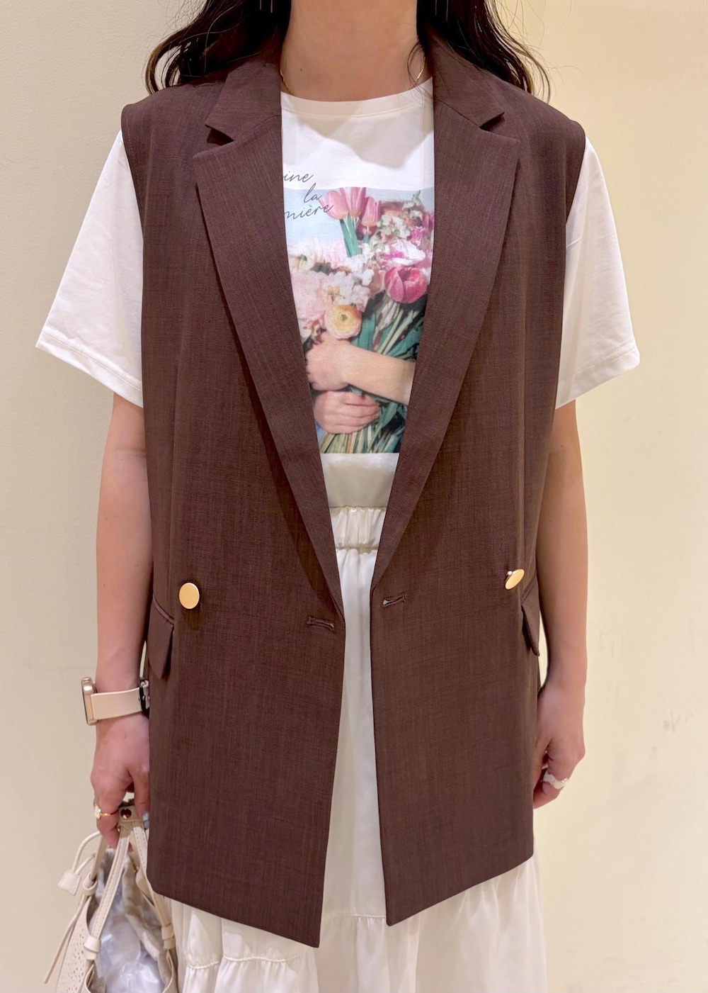 ホワイト系のスカート、ホワイト系のTシャツ/カットソー、ブラウン系のベストを着用したレディースの春コーディネートの6枚目の写真