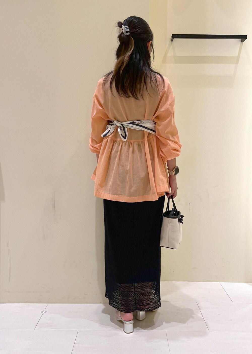 オレンジ系のシャツ/ブラウス、シルバー系のパンプス、ブラック系のトートバッグを着用したレディースの夏コーディネートの4枚目の写真