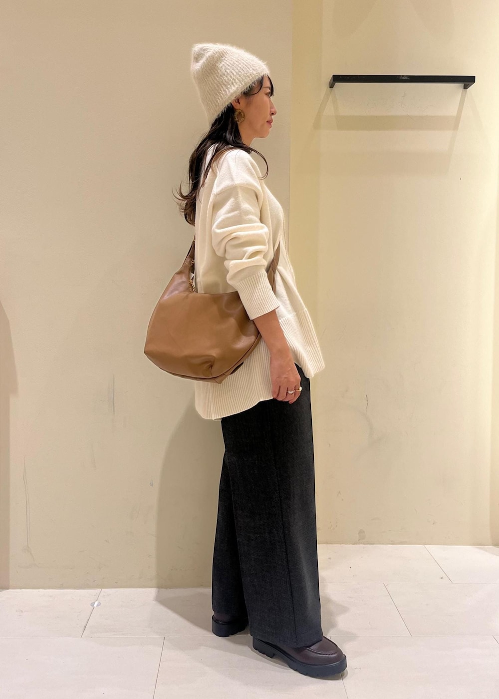 ホワイト系のニット/セーター、グレー系のスラックス、ブラウン系のローファーを着用したレディースの冬コーディネートの2枚目の写真