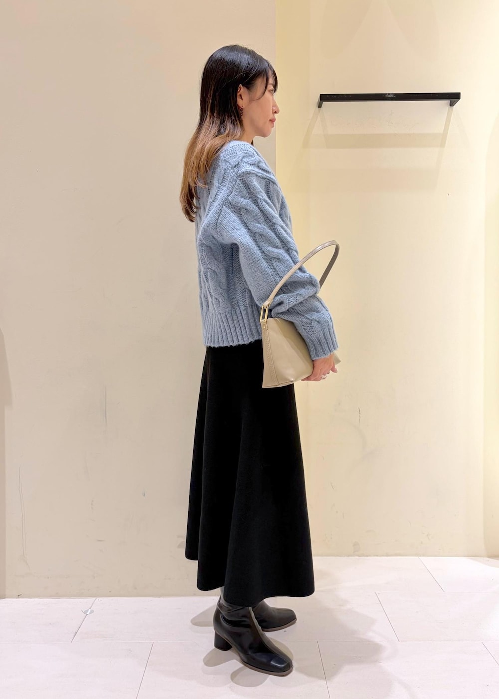 ブラック系のブーツ、ベージュ系のショルダーバッグ、ブラック系のワンピースを着用したレディースの冬コーディネートの3枚目の写真