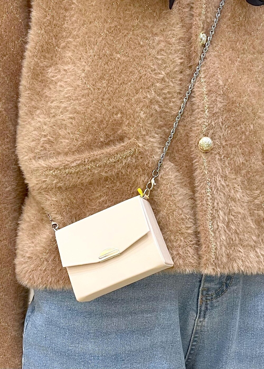 ブルー系のデニムパンツ、イエロー系のカーディガン/ボレロ、ホワイト系のショルダーバッグを着用したレディースの秋コーディネートの9枚目の写真