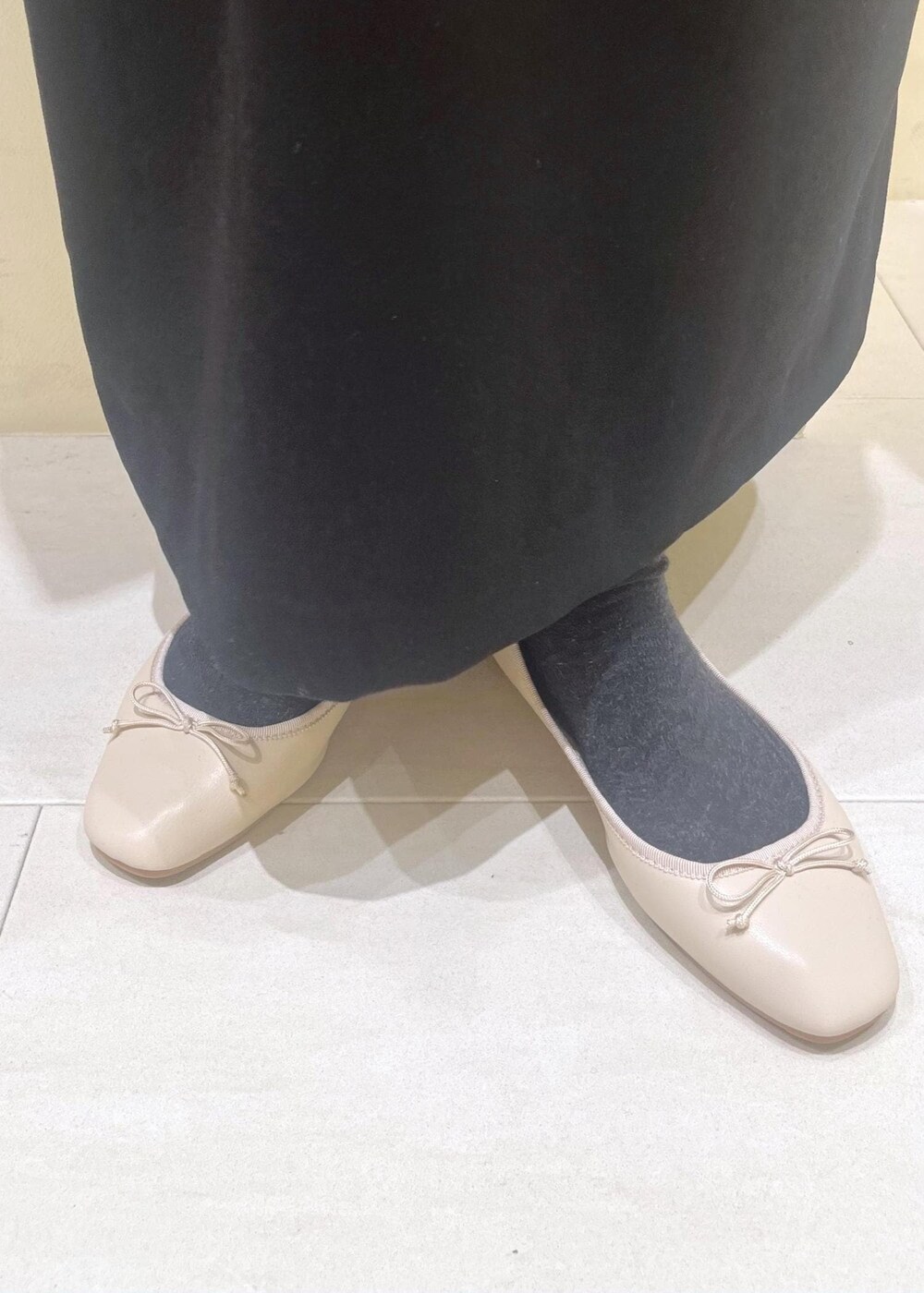 ホワイト系のバレエシューズ、ブラック系のショルダーバッグ、ブラック系のジャンパースカートを着用したレディースの冬コーディネートの9枚目の写真