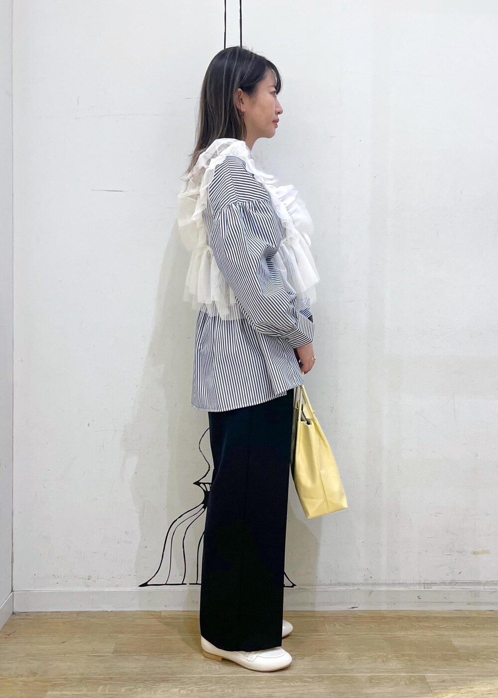 ホワイト系のベスト、ブルー系のその他パンツ、イエロー系のトートバッグを着用したレディースの冬コーディネートの3枚目の写真