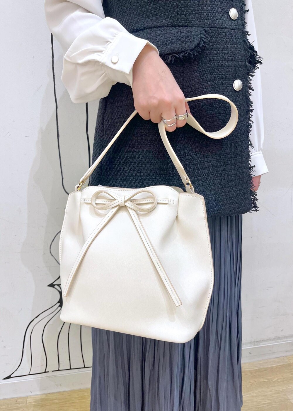 ブルー系のスカート、ベージュ系のローファー、ホワイト系のハンドバッグを着用したレディースの冬コーディネートの8枚目の写真