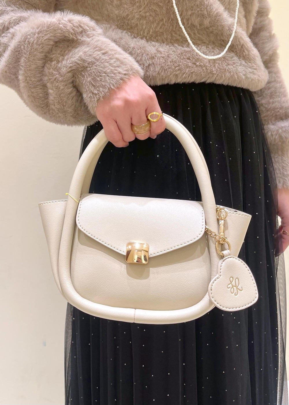 ホワイト系のショルダーバッグ、ブラック系のブーツ、ブラック系のスカートを着用したレディースの冬コーディネートの9枚目の写真