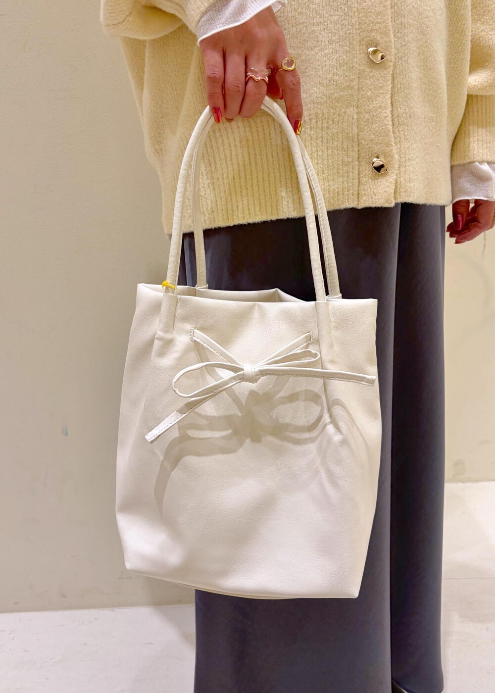 ベージュ系のカーディガン/ボレロ、ホワイト系のトートバッグ、ホワイト系のTシャツ/カットソーを着用したレディースの冬コーディネートの9枚目の写真