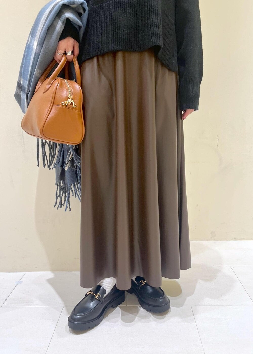 ブラウン系のスカート、ブラウン系のボストンバッグ、ブラック系のニット/セーターを着用したレディースの秋コーディネートの8枚目の写真