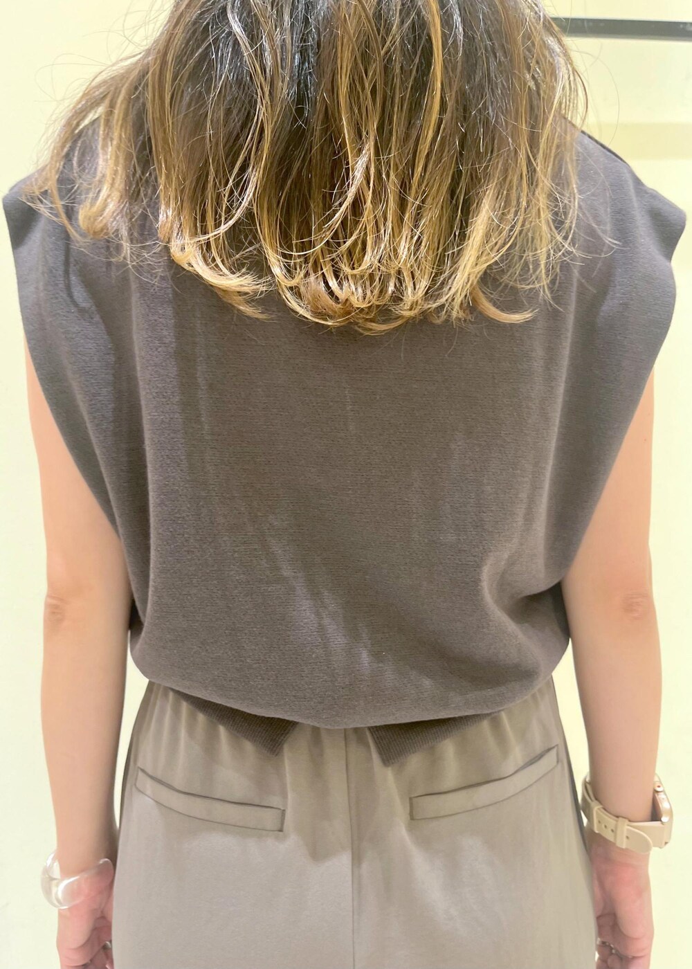 ゴールド系のサンダル、ベージュ系のハンドバッグ、グレー系のTシャツ/カットソーを着用したレディースの夏コーディネートの5枚目の写真