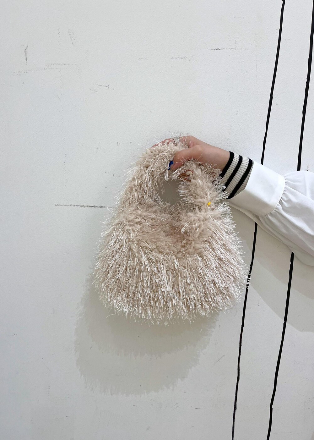 ベージュ系のハンドバッグ、ホワイト系のニット/セーター、シルバー系のバレエシューズを着用したレディースの冬コーディネートの10枚目の写真