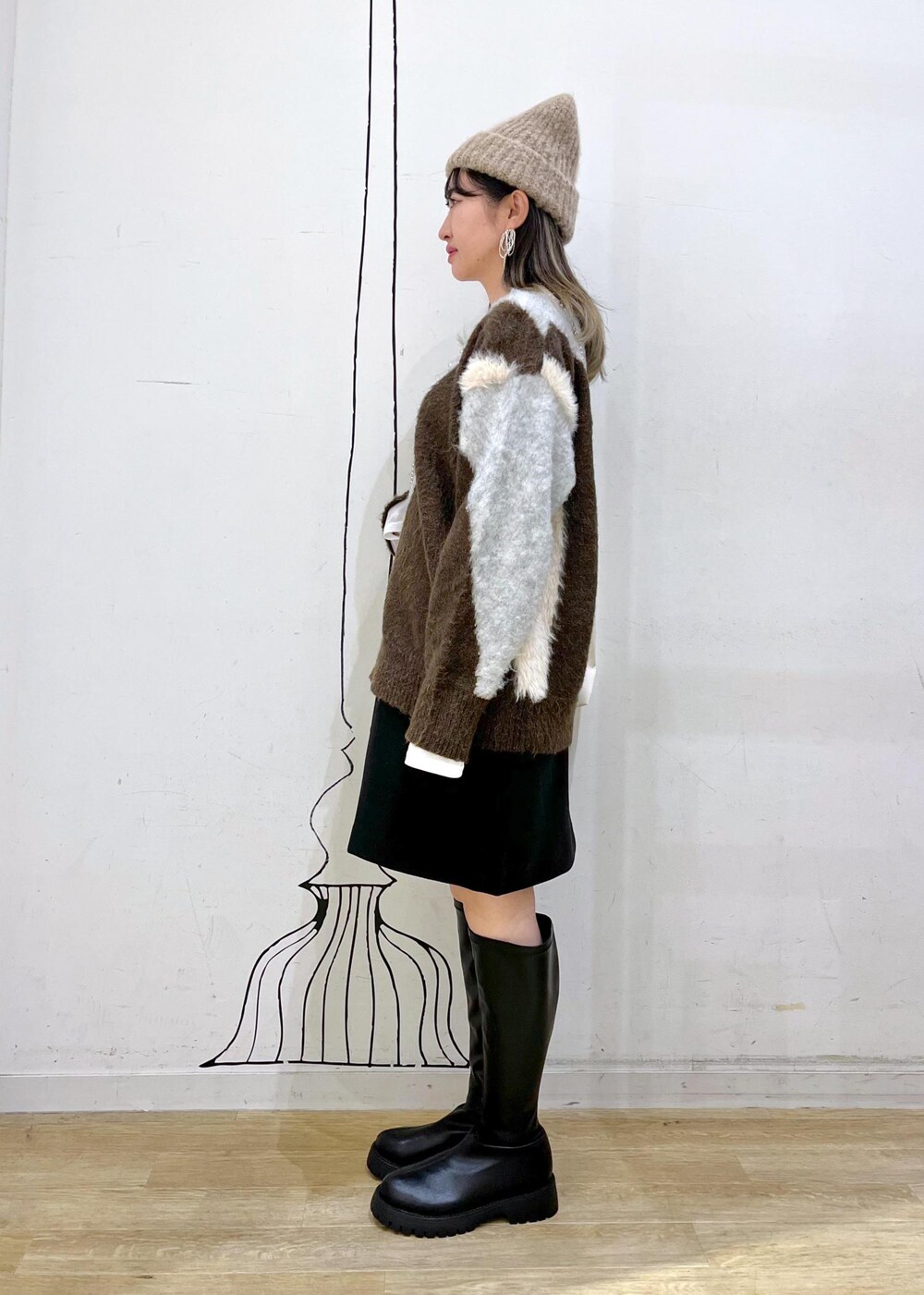 ブラック系のスカート、ブラック系のブーツ、ブラウン系のニット/セーターを着用したレディースの秋コーディネートの4枚目の写真