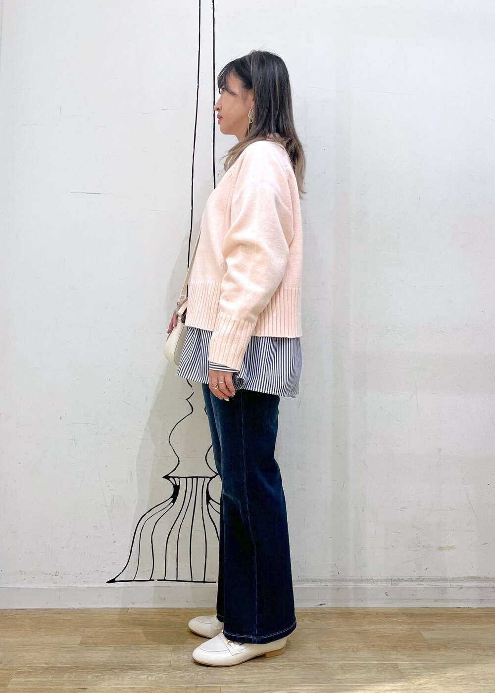 ピンク系のニット/セーター、ホワイト系のハンドバッグ、ブルー系のデニムパンツを着用したレディースの冬コーディネートの2枚目の写真