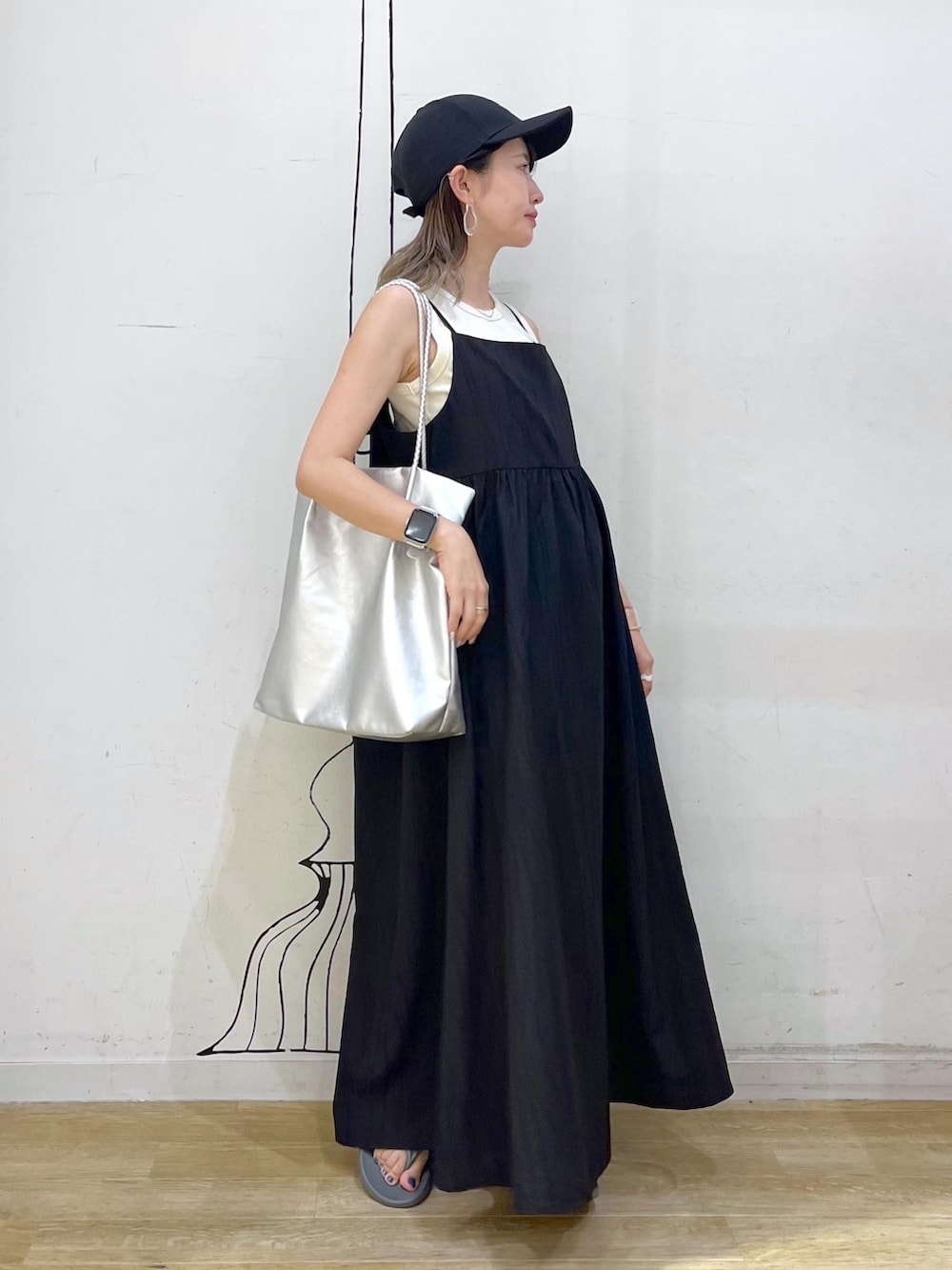 シルバー系のトートバッグ、ベージュ系のタンクトップ、ブラック系のワンピースを着用したレディースの夏コーディネートの3枚目の写真
